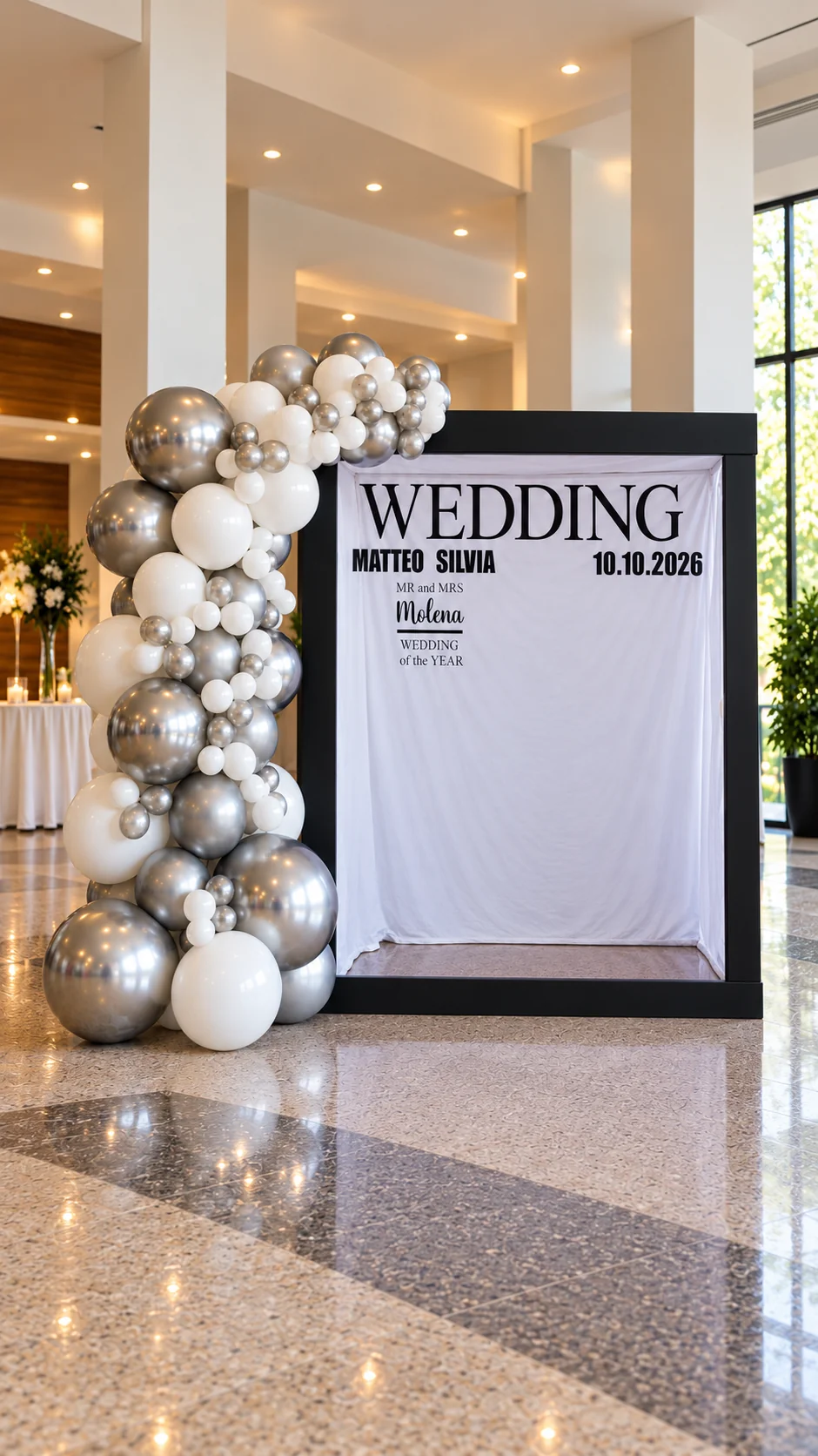 Photobooth a noleggio con composizione di palloncini bianchi e argento e fondale personalizzato per un matrimonio