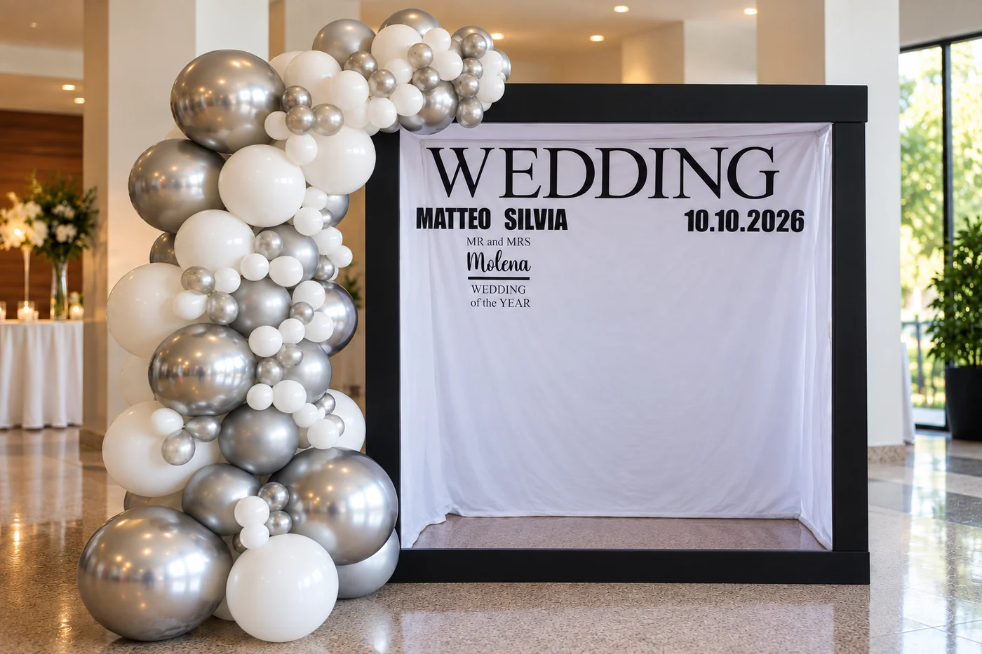 Photobooth a noleggio con composizione di palloncini e fondale personalizzato con nomi e data del matrimonio.