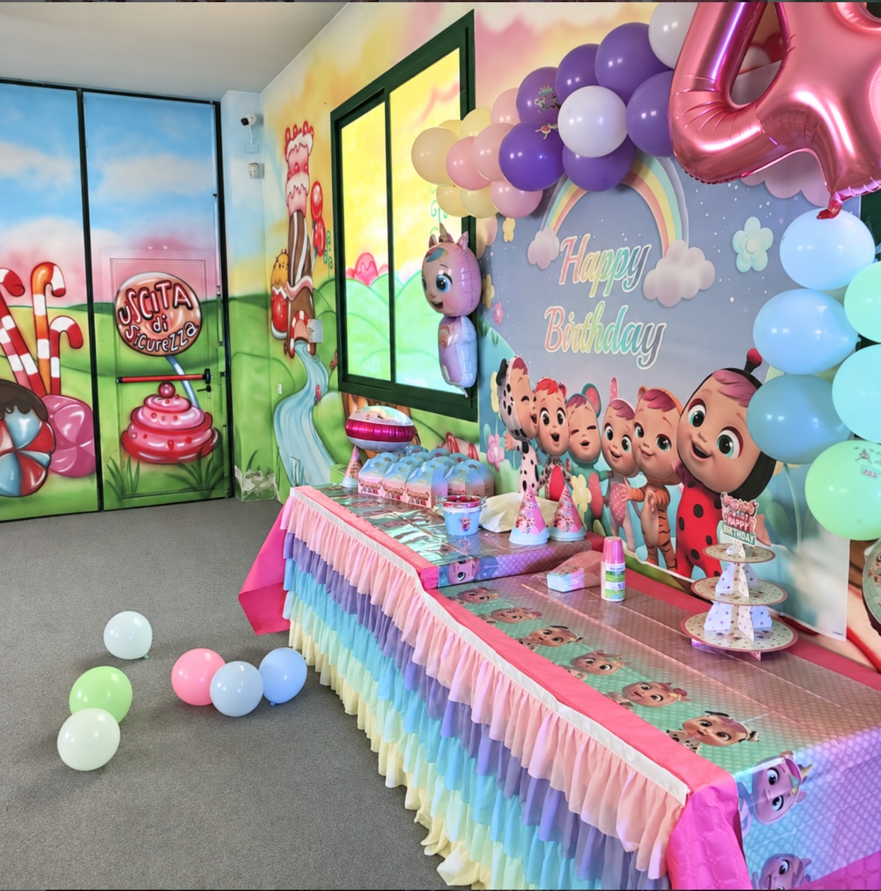 Allestimento della sala con palloncini pastello, backdrop e tavolo per il compleanno